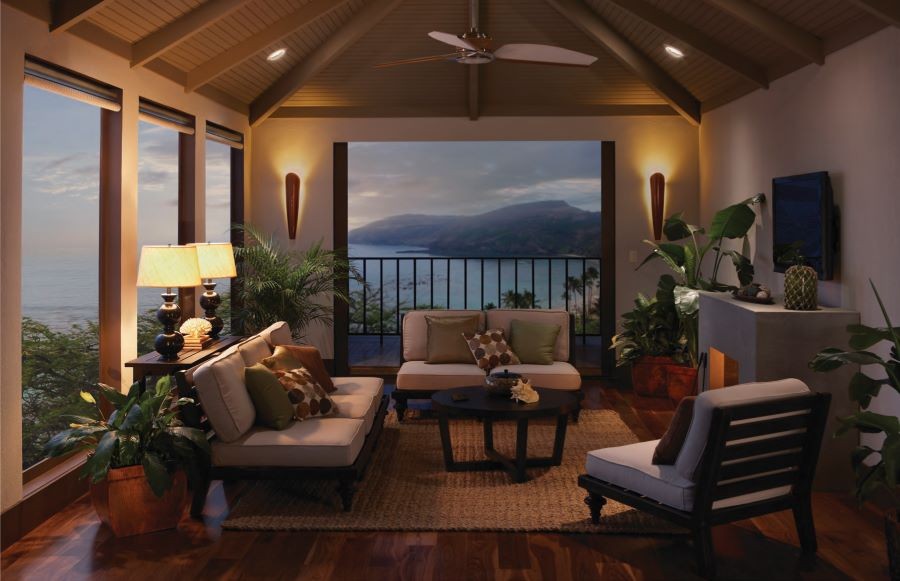 A living area with varying light fixtures and drawn shades overlooking the ocean. 